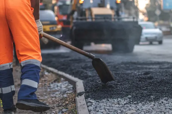 North Georgia asphalt repair worker laying fresh pavement to fix damaged road surfaces.